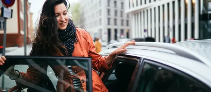 Woman getting into the back seat of a ride share