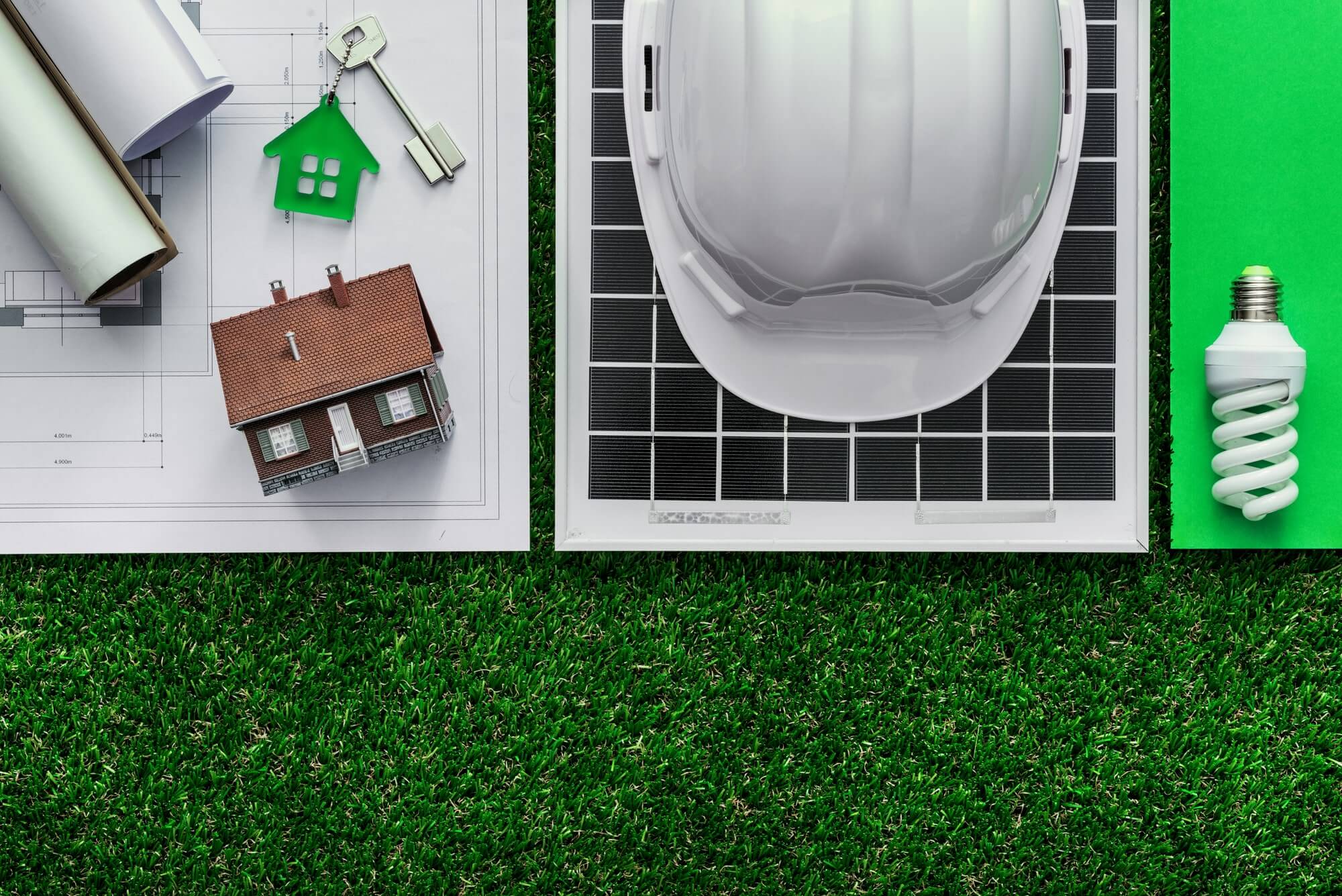 Navigating The Complex World Of Real Estate Disputes - hard hat on solar panel, house model, key, lightbulb, house plans, grass
