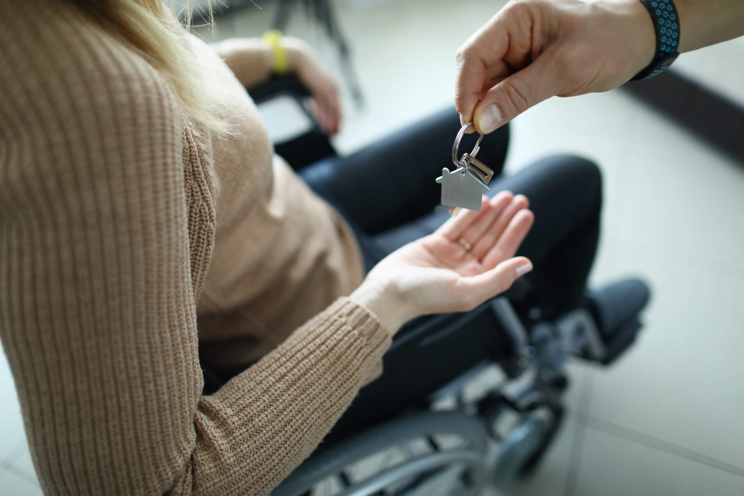 Tampa-HOA-Dispute-FAQs - Woman is sitting in wheelchair and keys are handed over to her.